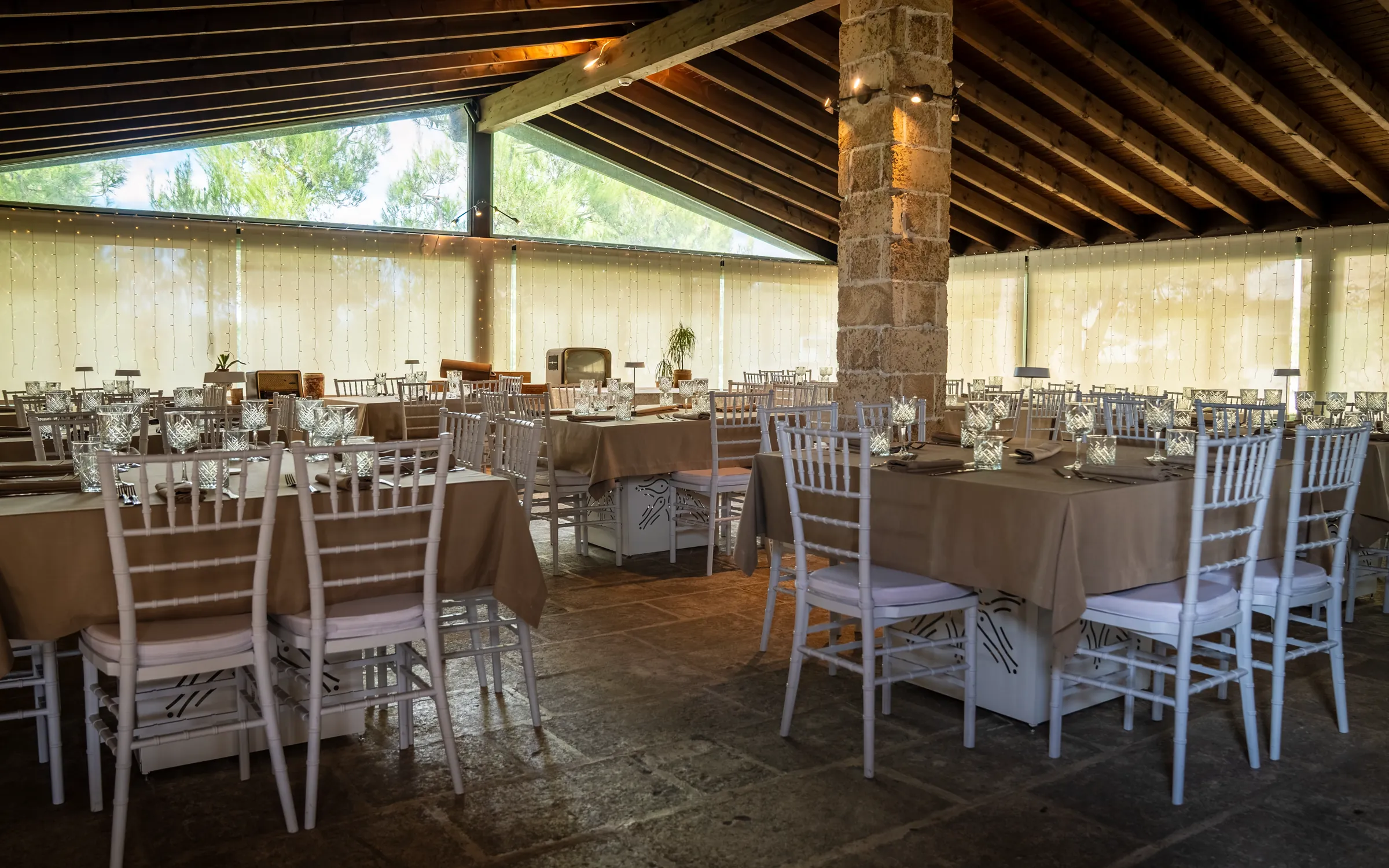 La sala degli archi apparecchiata, tra le colonne in pietra e le tende aperte sul verde